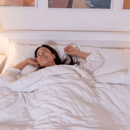 白いベッドで快適に眠る女性、リラックスした寝室の雰囲気